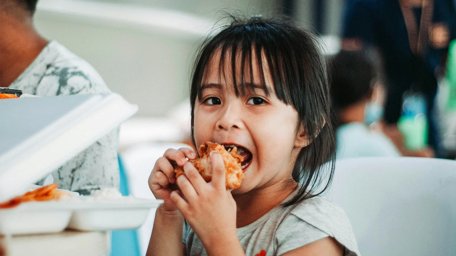 Niña sonriendo mientras come