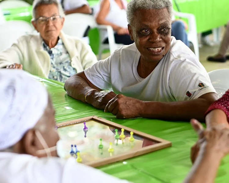 Adultos mayores jugando dominó y compartiendo en una mesa